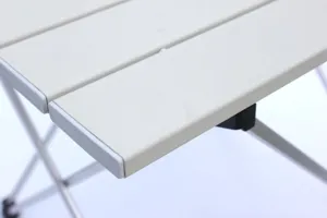 Primo piano dettagliato di un tavolo da campeggio pieghevole in alluminio con stecche e struttura.