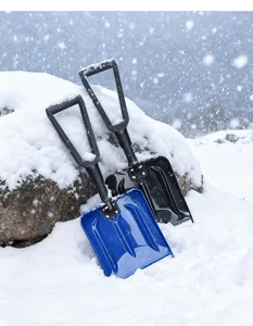 Detail view of portable plastic folding snow shovel, sturdy outdoor winter tool in snow.