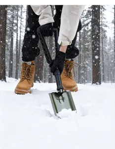 Vue détaillée de la pelle tactique pliante avec double poignée dans la neige.