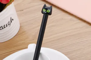 Primo piano del cappuccio a forma di testa di gatto nero su una penna gel carina