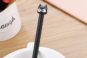 Dettaglio di una simpatica penna gel nera con gatto dei cartoni animati su scrivania.