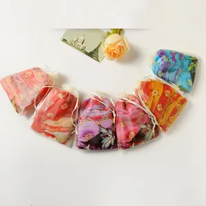 Detailoverzicht van kleurrijke bedrukte chiffon sjaals in witte organza cadeauzakjes
