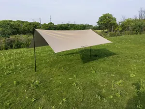 Bâche de camping en plein champ vert, abri solaire résistant idéal pour pique-nique et randonnée.
