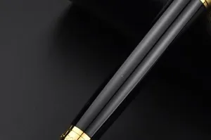 Close-up detail of luxury business metal rollerball pen with sleek black barrel and gold clip.