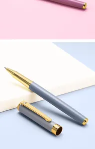 Detailed close-up view of luxury metal rollerball pen with Morandi grey barrel and gold trim.