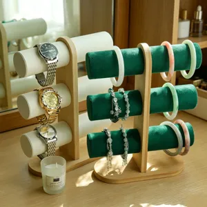 Detail van een bamboe sieradenstandaard met drie niveaus, groen fluweel en witte leren rollen