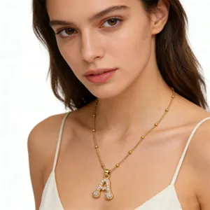 Close-up detail of the gold letter A pendant necklace with sparkling zircon stones worn by model.