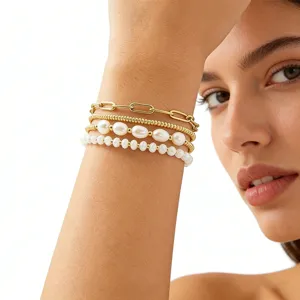Gros plan détaillé présentant l'élégant ensemble de bracelets superposés en or et perles.