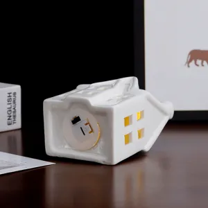 Wit keramisch huis nachtlampje en kaarshouder met holle ramen voor huisdecoratie.