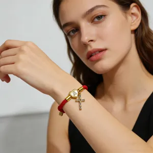 Primo piano di un elegante bracciale in corda rossa intrecciata con ciondolo a cuore e croce.