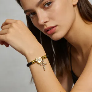 Primo piano dettagliato di un elegante braccialetto placcato oro con croce e lettera M.