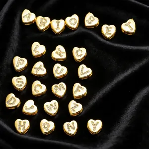 Ciondoli alfabeto a cuore dorato intarsiati con strass scintillanti su tessuto di velluto.