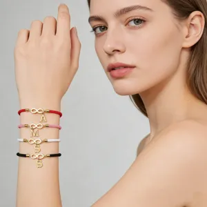 Close-up detail of handmade woven couple bracelets with gold infinity symbol and letter charms.