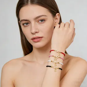 Handmade woven couple bracelets with gold infinity symbol and alphabet letter charms for daily wear.