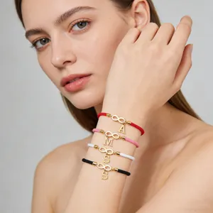 Detailed close-up of handmade woven string charm bracelets featuring infinity symbol and letters.