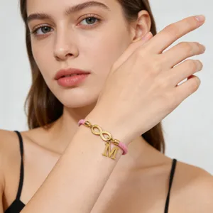 Handmade pink braided bracelet with infinity symbol and letter charm for daily wear style.