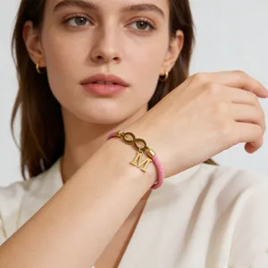 Detail view of the pink braided rope bracelet showing gold infinity and letter M charm.