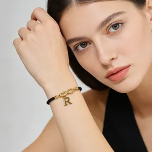 Handmade black woven cord bracelet featuring a gold letter R pendant and infinity charm.
