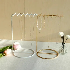 White and gold iron jewelry organizers showing necklaces on a minimalist lifestyle setting