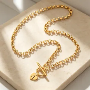 Gold initial heart pendant necklace detail, toggle clasp design, elegant clavicle chain.