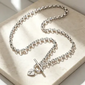 Close-up detail of silver chain necklace with heart pendant letter A and elegant T-bar clasp.