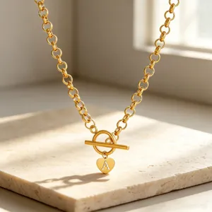 Detail shot of a gold chunky chain necklace featuring a toggle clasp and heart letter A pendant.