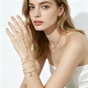 Primo piano del bracciale schiava con iniziale in acciaio dorato e catene con perline.