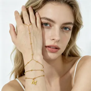 Dettaglio in primo piano del bracciale a catena multistrato in acciaio con ciondolo lettera M.