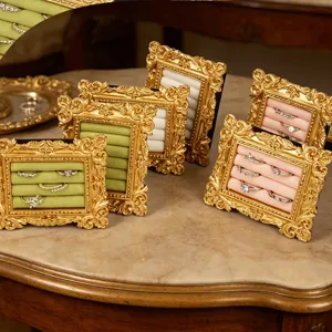 Elegantes expositores de anillos vintage dorados con ranuras de terciopelo sobre mármol.