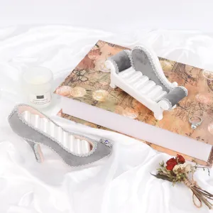 Présentoirs à bijoux de luxe en velours gris en forme d'escarpin et de canapé sur soie.
