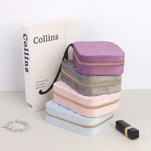 Stack of colorful velvet travel jewelry boxes with quilted lids and gold zippers