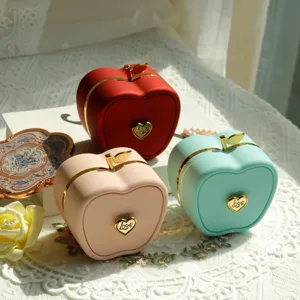 Detailed view of three apple-shaped jewelry boxes in red, pink, and mint green.