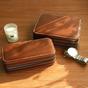 Close-up of vintage brown leather watch boxes with white stitching and zipper closure