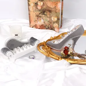 Présentoirs de bagues en velours gris en forme de chaussure et canapé sur satin blanc