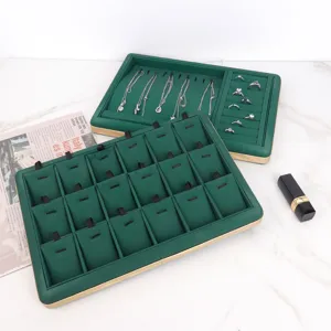 Detail view of green velvet jewelry display tray with necklace hooks and ring slots