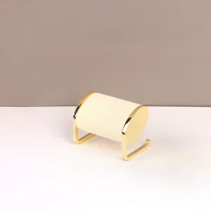 Detail van een minimalistische sieradenhouder van crème fluweel met een goudkleurig metalen frame