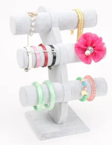 Detail van een drielaagse grijze fluwelen sieradenstandaard met diverse armbanden.