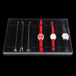 Detailed view of black 10-grid display tray holding watches and necklaces