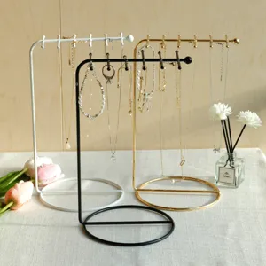 Detailed view of three metal jewelry display stands in black, white, and gold finishes