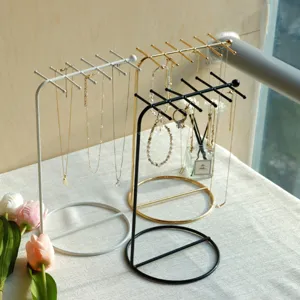 Elegant iron jewelry stands in white, gold, and black finishes displayed on a table.