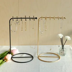 Detailed view of minimalist black and gold iron jewelry stands displaying necklaces
