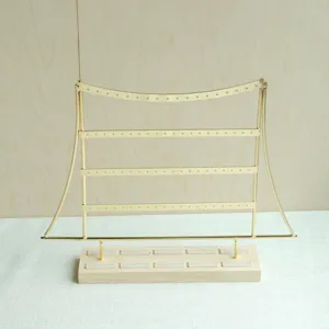 Detail eines 4-stufigen goldenen Ohrringhalters mit minimalistischer Holzbasis für Schmuck