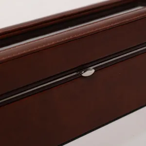 Détail de la boîte à montres en cuir marron avec bouton pression argenté et coutures