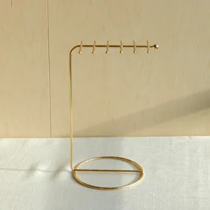 Close-up of a minimalist golden metal jewelry stand for necklaces and bracelets.