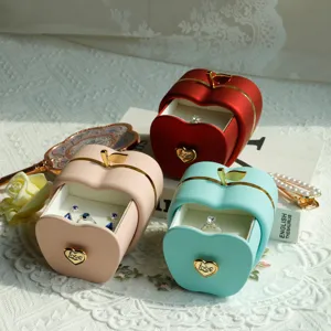 Detailed view of decorative apple-shaped jewelry boxes in red, pink and teal colors