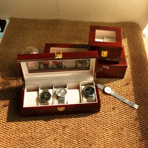 Cajas de madera lacada en rojo para relojes con 2 y 5 compartimentos sobre tapete