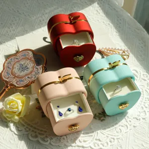 Detail of red pink and mint green apple-shaped jewelry boxes with gold heart handles