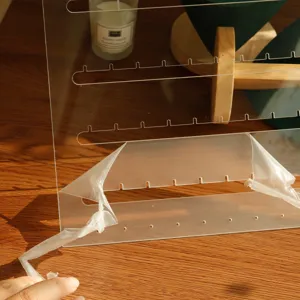 Detailed view of clear acrylic earring organizer with protective film being peeled