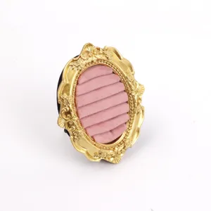 Detailed macro view of vintage gold resin jewelry frame with soft pink velvet slots