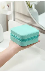 Close-up view of a compact mint green portable jewelry storage box held in a hand